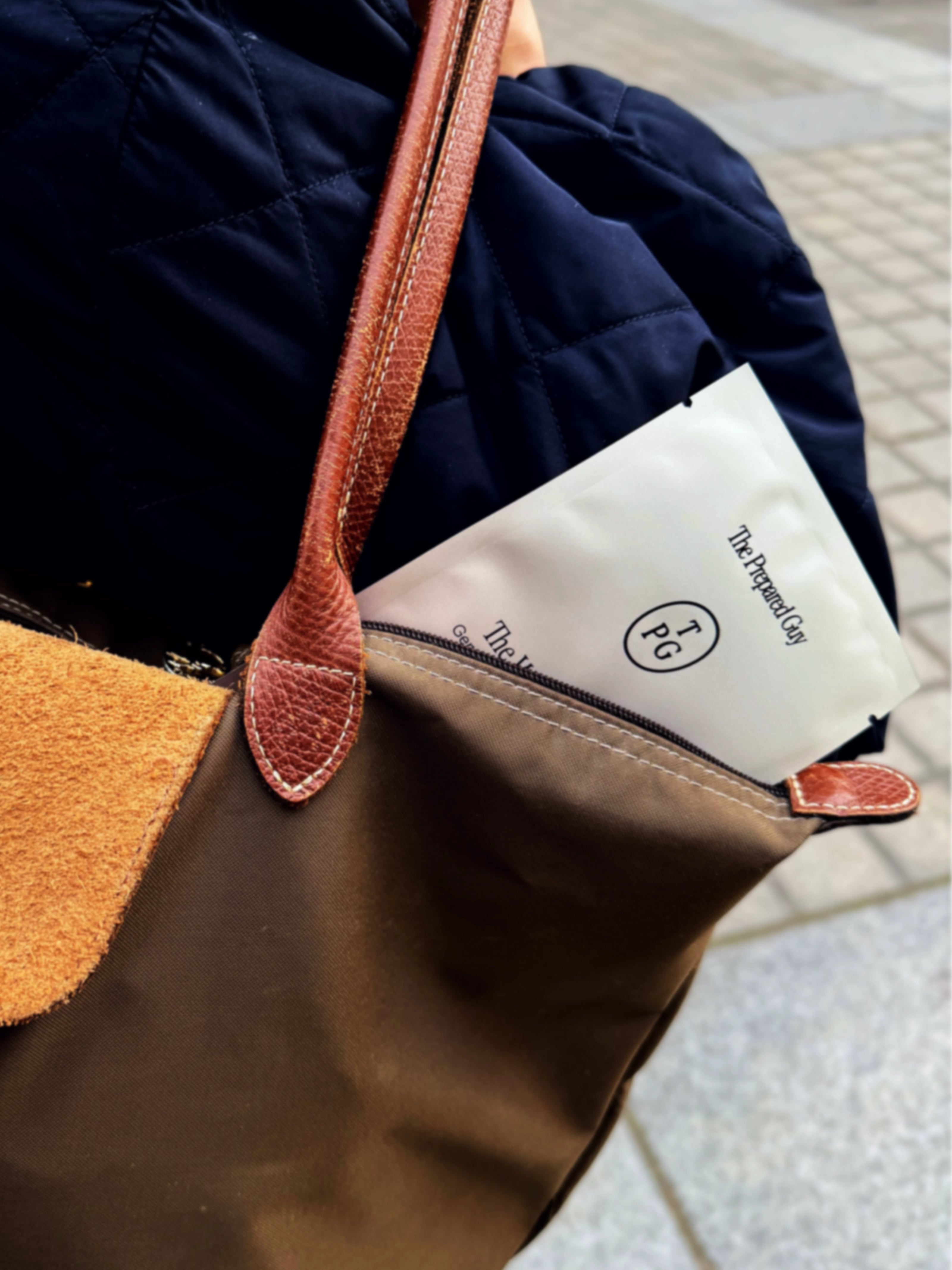 Brown leather handbag with a visible The Prepared Guy brand product inside