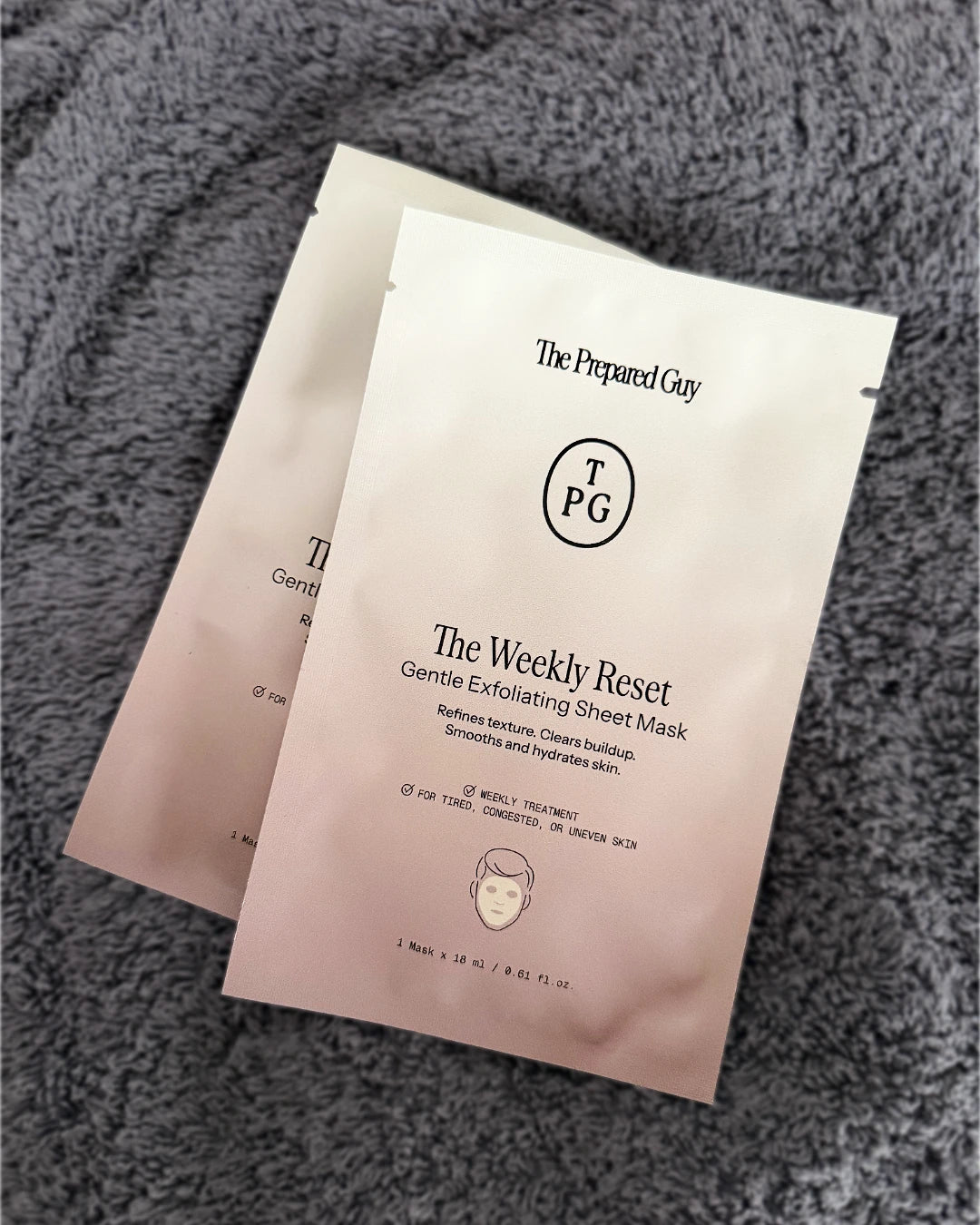 Two 'The Weekly Reset' sheet masks by The Prepared Guy on a textured gray surface.