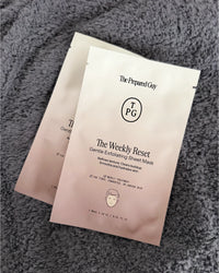 Two 'The Weekly Reset' sheet masks by The Prepared Guy on a textured gray surface.