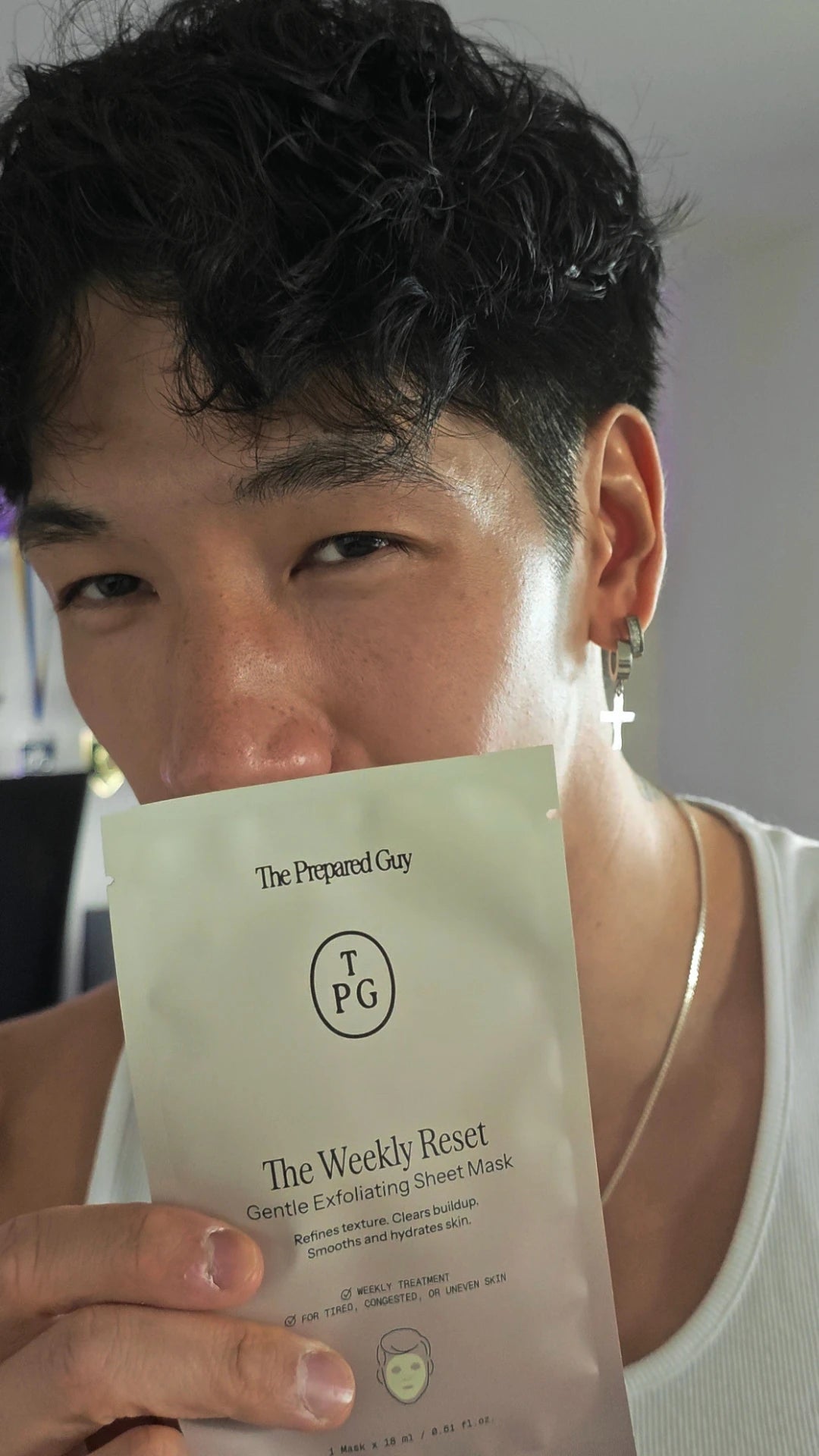 Man holding a sheet mask sachet in front of him