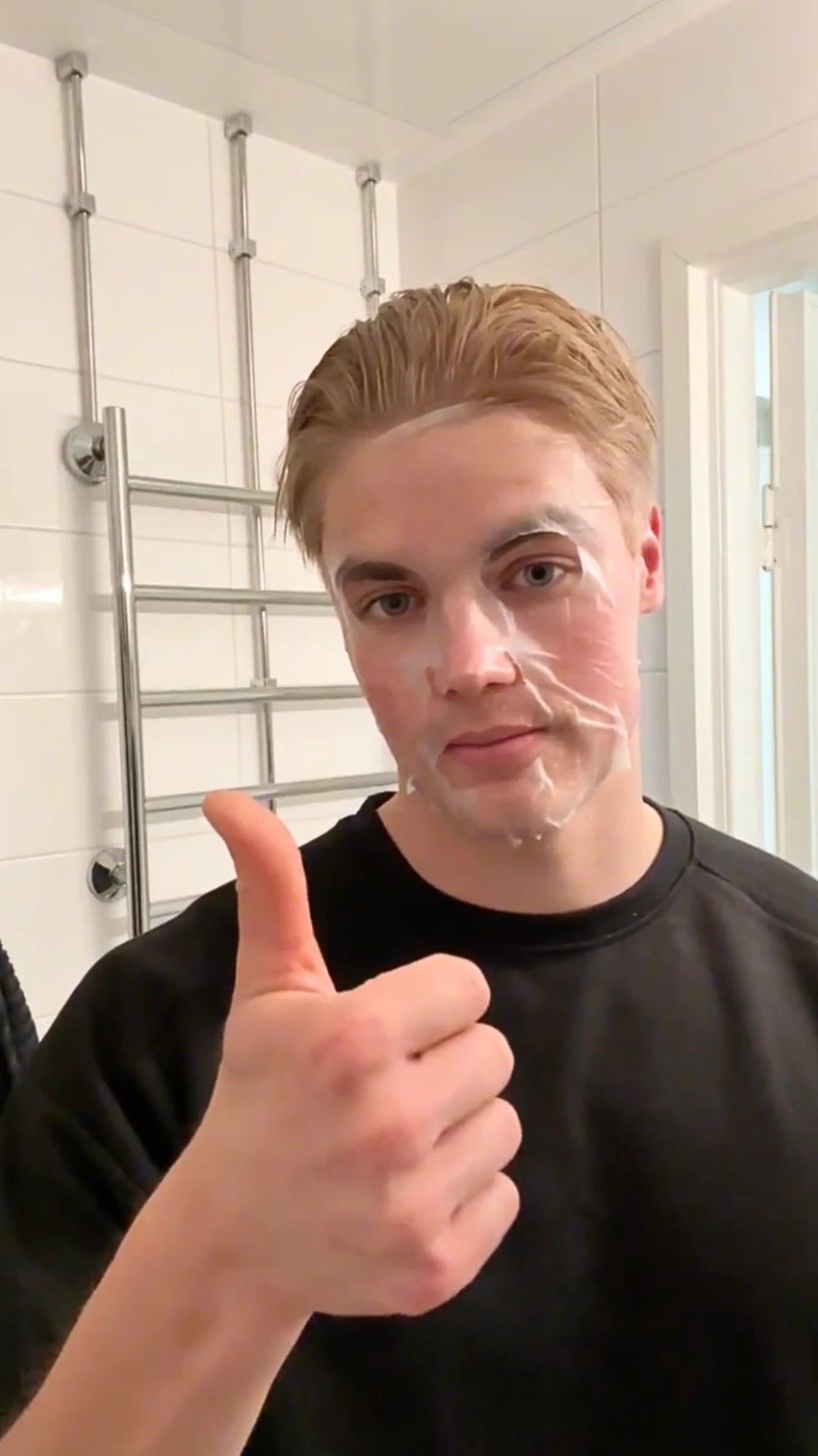 Man with a facial sheet mask on showing thumb up