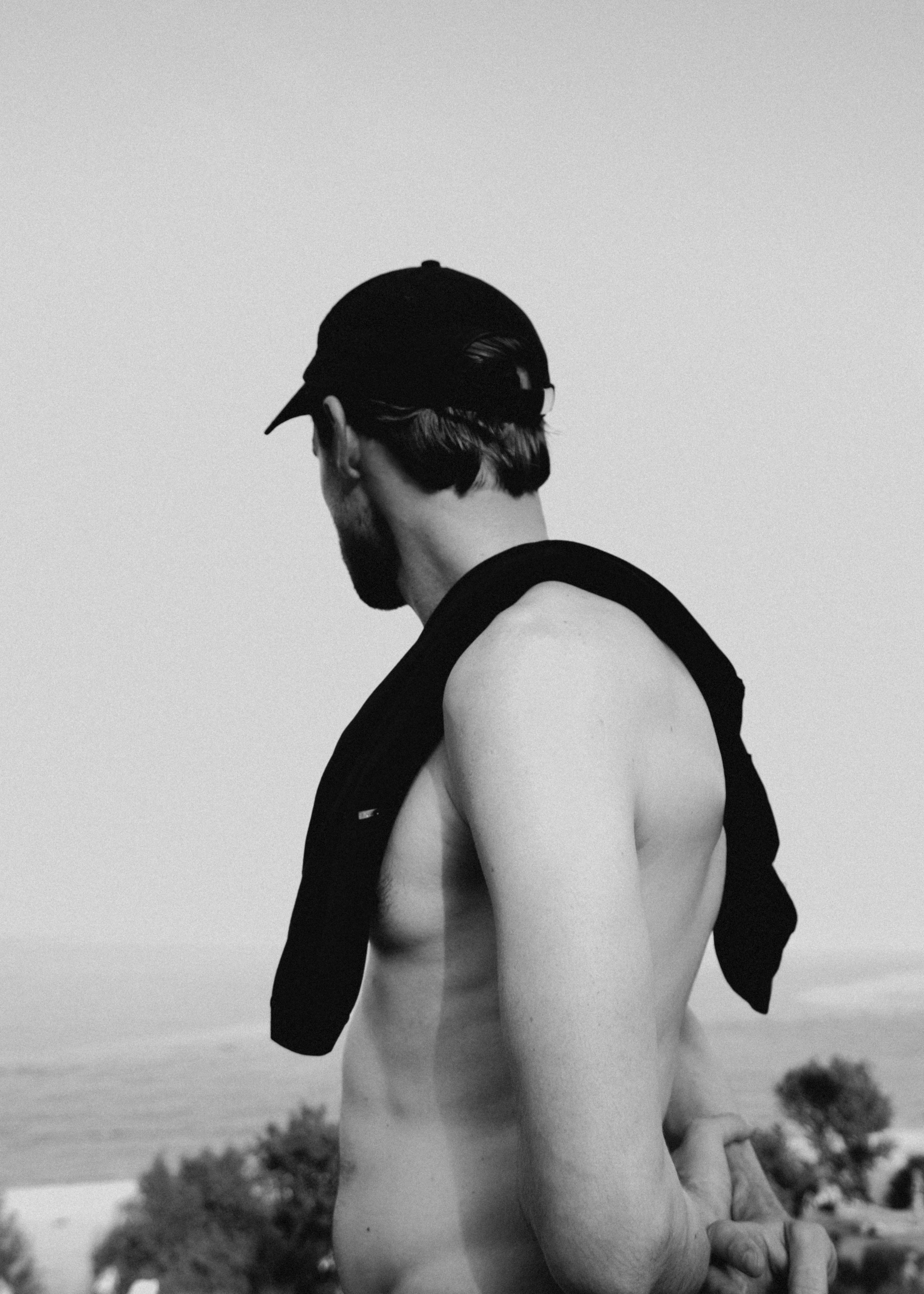Man with a towel draped over his shoulder, standing by a body of water.
