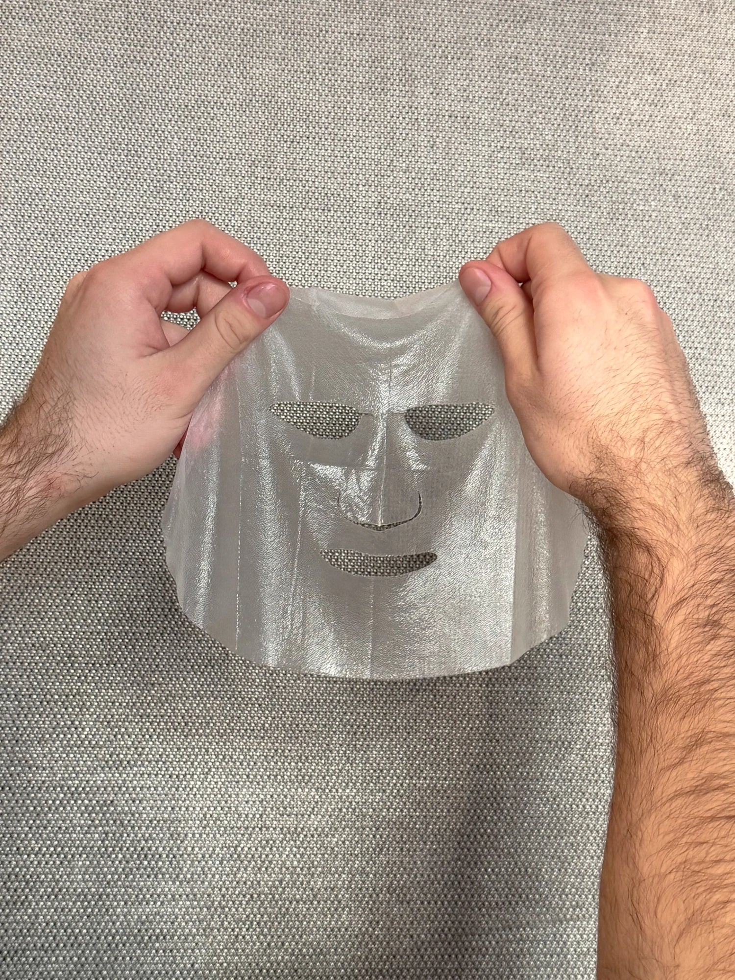 A man holding a sheet mask in his hands