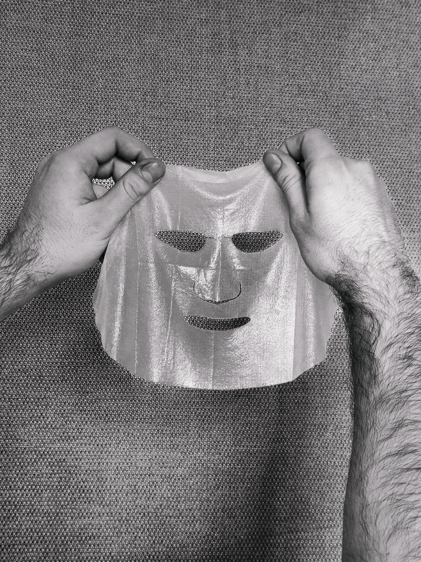 Person holding a sheet mask against a textured background